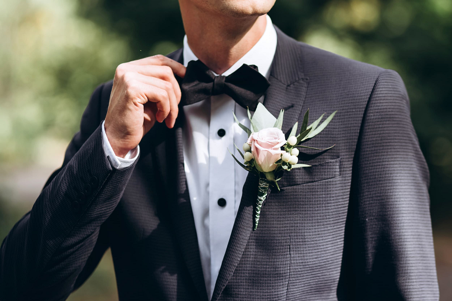 A man wears a black tuxedo to a wedding.